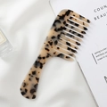 Macro detail of wide-tooth acetate hair comb with elegant tortoiseshell marble patterns - Beige