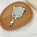 Détail d'un miroir de maquillage à main avec motif marbre noir et blanc sur plateau - Mélange Noir et Blanc