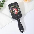 Detail view of a black unicorn air cushion hairbrush with stars on white satin - Unicorn Wreath
