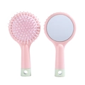 Pink mini hairbrush with integrated vanity mirror and massage bristles on white background - Pink
