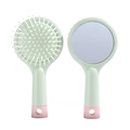 Detail of macaron green cushion hairbrush with built-in makeup mirror and soft bristles - Green