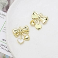 Detail shot of bright gold bow and heart charms with white oil drip on ceramic plate - Solid Heart Bow (28# Gold Tone)