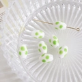 Close-up of white oval ceramic beads with green polka dots and a gold metal pin detail - White with Green Polka Dot (5#)