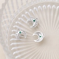 Macro shot of silver crescent moon charms with green gemstones and micro-bead detail - White Gold