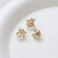 Detailed view of three golden dolphin alloy charms with pink beads on a white ceramic plate - Gold Dolphin With Pink Sphere