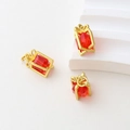 Macro view of gold-plated gift box pendant with red crystal and bow detail - Red