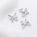 Macro shot of silver butterfly charms with butterfly-shaped cubic zirconia and hollow design - White Gold
