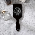 Close-up of black air cushion brush with sun and moon art on a textured marble surface - Sun Moon Pattern