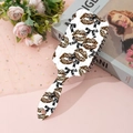 Detailweergave van roze haarborstel met luipaardprint en strik op een bloemige achtergrond - Luipaard Lippen Strik Stijl (A)
