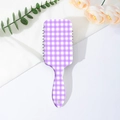 Nahaufnahme der lavendelfarbenen Gingham-Paddelbürste auf floralem Hintergrund - Lila Karomuster