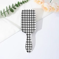 Detailed view of checkered print air cushion hairbrush with ergonomic handle and hanging hole - Black & White Check