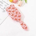 Dettaglio spazzola rosa con stampa a fiocchi e setole a cuscino d'aria su fondo bianco - Motivo con Fiocco e Cuoricino (D)