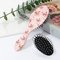Dettaglio della spazzola per capelli rosa con fiocchi e cuori su un tavolo bianco - Motivo Fiocco Rossetto (A)