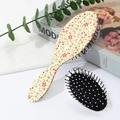 Detail of floral air cushion hairbrushes showing patterned back and black massage bristles - Beige Floral (B)