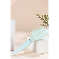 Pale green pearlescent air cushion massage comb on a minimalist decorative background - Blue