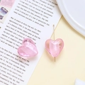 Makroaufnahme von rosa Herzglasperlen und Goldnadel für DIY-Schmuckherstellung - Rosa