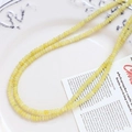 Macro shot of natural yellow agate beads arranged in an S-curve on a white ceramic plate - Yellow (3# Single Strand)