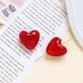 Macro di orecchini a cuore in vetro rosso su una rivista per design di gioielli DIY - Rosso