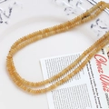 Detailed view of yellow agate round beads on a ceramic plate with vintage magazine accents - Yellow Round (8# Single Strand)