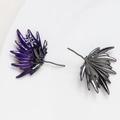 Dettaglio di orecchini a perno a piuma viola con zircone blu e finitura gunmetal - Canna di fucile