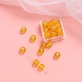 Makroaufnahme von bernsteinfarbenen Glasperlen für DIY-Schmuck auf rosa Grund - Blassorange