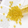 Macro shot of 4mm yellow glass seed beads with gold foil poured from a plastic tube - Yellow