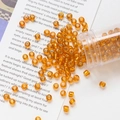 Vista macro de cuentas de vidrio ámbar de 4mm en tubo para creación de joyas DIY - Naranja