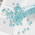 Detail of 4mm light blue silver-lined glass seed beads scattered near a clear storage jar - Lake Blue
