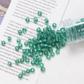 Macro shot of 4mm emerald glass seed beads with silver lining for DIY jewelry making - Green