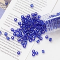 Macro shot of 4mm blue purple glass seed beads pouring from a tube for DIY jewelry making - Deep Blue