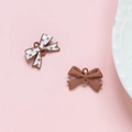 Macro-opname van twee bruine strikvormige hangers van legering voor DIY-sieraden op roze basis - 7# Koffie Witte Ster Strik