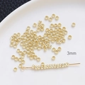 Vue macro de perles à écraser dorées de 3mm pour création de bijoux sur plat blanc - 3mm / Or 14 carats