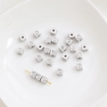 Macro shot of silver cube spacer beads with smiley faces for DIY jewelry making - Silver