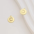 Macro view of gold-plated circular letter C pendant with sparkling cubic zirconia inlay - Letter C / Gold