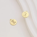 Detail of gold plated letter E pendant with cubic zirconia inlay on white stone - Letter E / Gold
