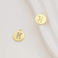Macro detail of 18k gold plated round letter K charms with cubic zirconia inlay and laser cuts - Letter K / Gold