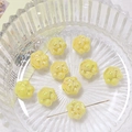 Macro detail of yellow ceramic cat paw beads with metal needle showing the drill hole - Yellow