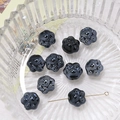Macro shot of glossy black ceramic cat paw beads with gold pin for DIY jewelry making - Black
