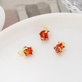 Makroaufnahme von drei roten Emaille-Rosenanhängern mit Goldösen für DIY-Schmuckherstellung - Chinesischer Goldstil