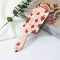 Close-up of pink air cushion hairbrush with strawberry and floral pattern on a desk - Pink Strawberry Cherry Style (A)