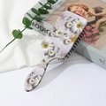 Détail d'une brosse à cheveux à motif floral et perles sur un magazine moderne - Style de Fleur B