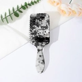 Detail of grey glitch art pattern on the back of a paddle hairbrush with hanging hole - Pattern B (Glitch Pixel)