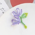 Macro shot of handcrafted beaded flower brooch with purple crystal petals and green stems - Purple Double Flower