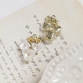 Dettaglio di ciondoli a fiore in lega con perle su sfondo di carta vintage - Stile Tre Fiori / Bianco