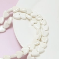 Close-up of heart-shaped ceramic beads with pearl luster for DIY jewelry making - White