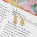 Close-up of gold-plated hand pendant holding heart-shaped zircon on artistic book page - 3# Hand Holding Zirconia