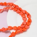 Macro shot of red heart-shaped ceramic beads for DIY jewelry with center holes - Orange