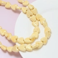 Detailed close-up of cream yellow heart-shaped ceramic beads on a white porcelain plate - Milky Yellow