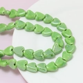 Macro shot of green heart-shaped ceramic beads for DIY jewelry with glossy finish - Green