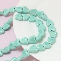 Macro shot of mint green heart-shaped ceramic beads for DIY jewelry making - Cyan